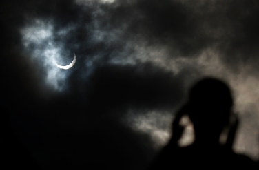 Tourist watches as the moon passing in front of the sun as it approaches a full solar eclipse in the northern Australian city of Cairns